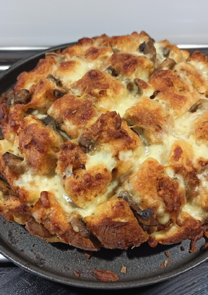 Una foto de Hogaza de ajo, queso, tomate y champiñones