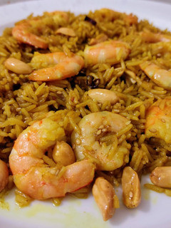 Una foto de Arroz jazmín frito con curry, cacahuetes, sésamo, miel y langostinos