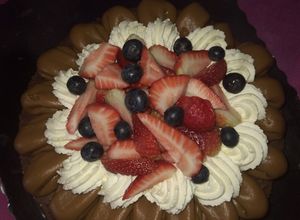 Una foto de Brownie con dulce de leche, Chantilly, frutillas y arándanos