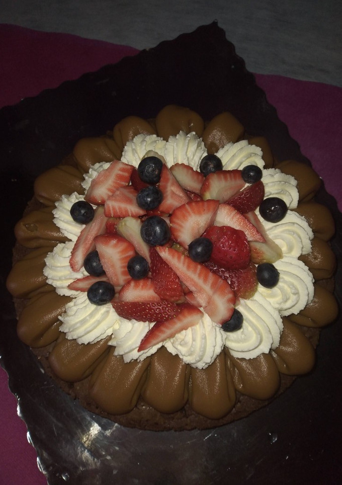 Una foto de Brownie con dulce de leche, Chantilly, frutillas y arándanos