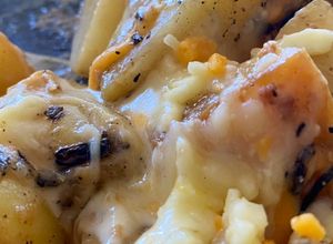Una foto de Papas al ajo y romero con gratín de cheddar y mozzarella