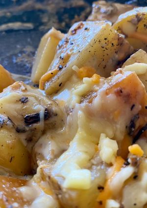 Una foto de Papas al ajo y romero con gratín de cheddar y mozzarella
