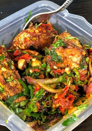 A picture of Boiled plantain and fish in green vegetable sauce.