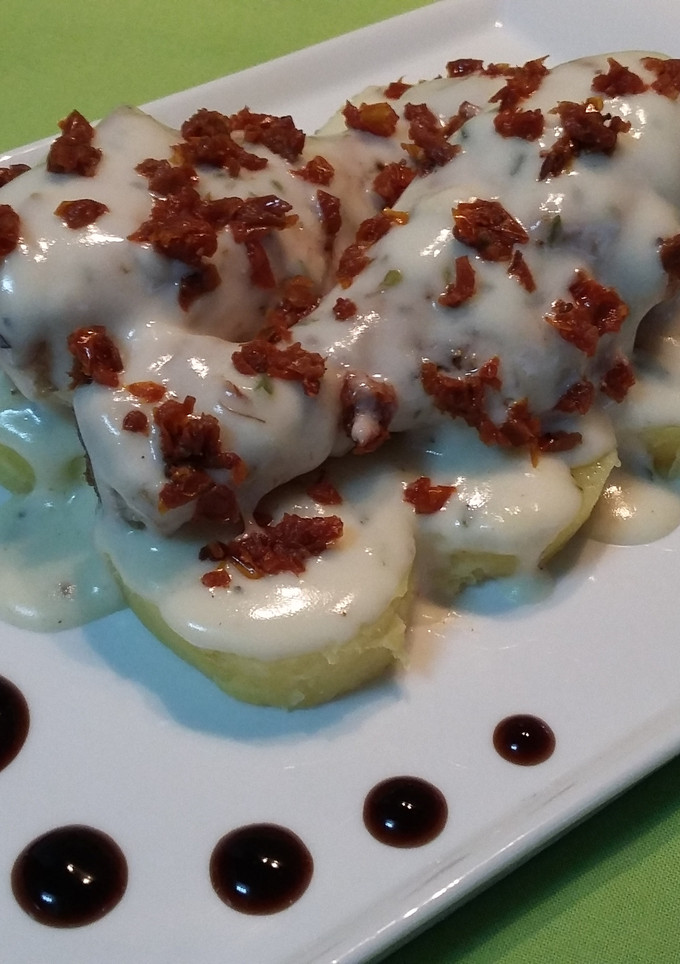 Una foto de Muslos de pollo con bechamel al orégano y tomates secos