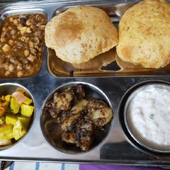 A picture of Aloo, Puri, white chane with salad and kheer.