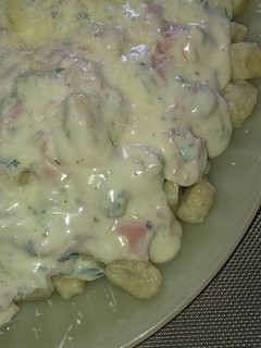 Una foto de Ñoquis de papa, con salsa blanca
