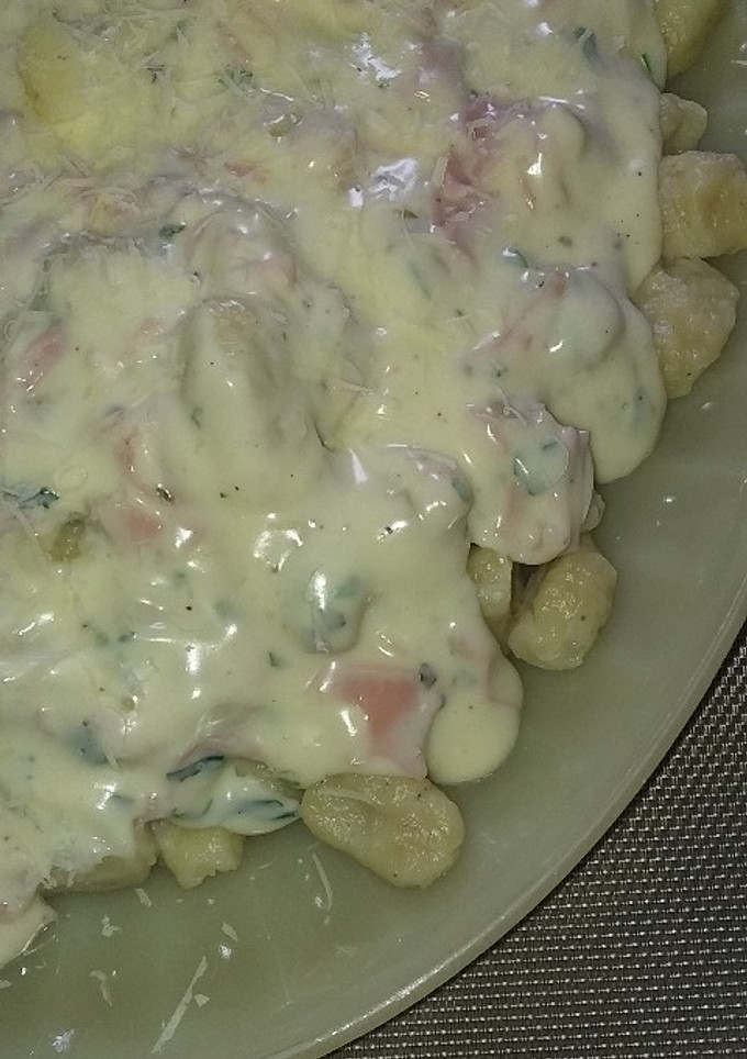 Una foto de Ñoquis de papa, con salsa blanca