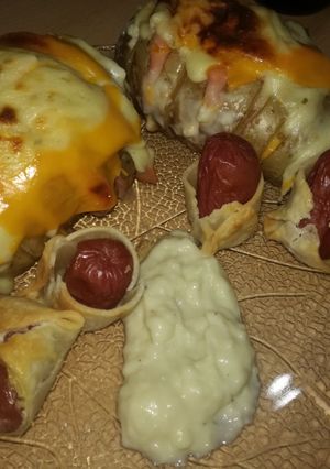 Una foto de Papa rellenas con niño envuelto y salsa blanca