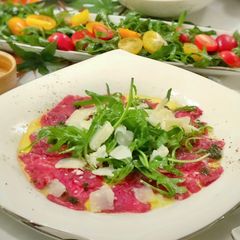 A picture of Beef Carpaccio with Arugula, pesto oil and truffle paste.