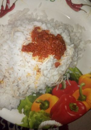A picture of Ofada rice with pasta and palm oil stew.