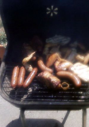 A picture of grilled hot dogs wrapped in hamburger and bacon.