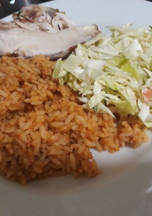 A picture of Jollof rice with coleslaw and chicken.