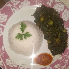 A picture of White rice and garden egg leaves soup.