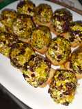 Bombones de queso y crujiente de jamón con cobertura de pistacho y arándanos