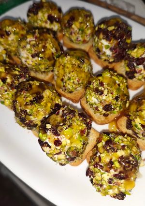 Una foto de Bombones de queso y crujiente de jamón con cobertura de pistacho y arándanos