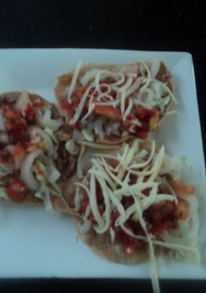 Una foto de Tostadas de cueritos encurtidos, salsa de birria y queso rallado rancheras. México