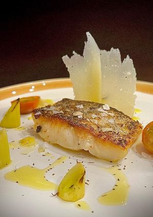 Una foto de Merluza con puerro asado y láminas de queso curado de oveja