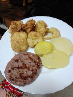 Una foto de Hamburguesa de cerdo a la plancha con coliflor rebozada y papas cocidas