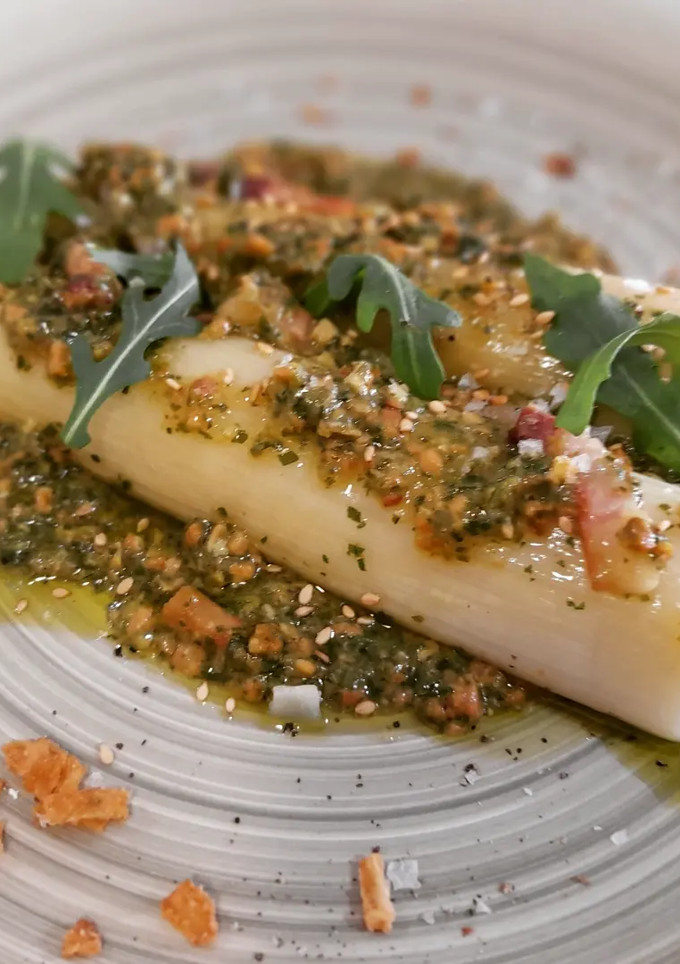 Una foto de Puerros confitados con panceta y pesto de rúcula y pistachos