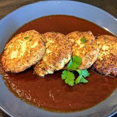 A picture of Cauliflower and cheese cakes in chile ancho sauce.