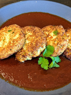 A picture of Cauliflower and cheese cakes in chile ancho sauce.