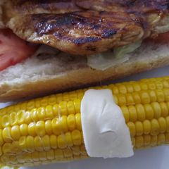 A picture of BBQ chicken panino with buttered Corn on the cob.