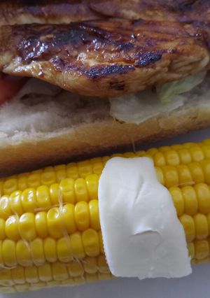 A picture of BBQ chicken panino with buttered Corn on the cob.