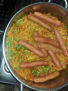 A picture of Spaghetti jollof and beef sausage.