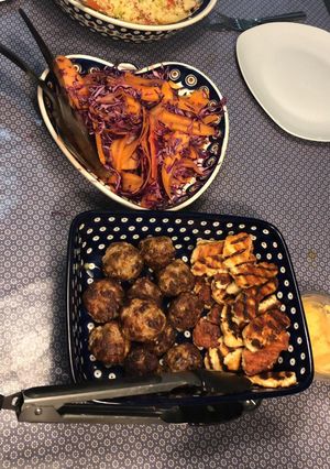 A picture of Lambs kofta with grilled halloumi, tzatzici and pickled carrot and red cabbage.