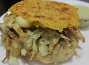 Una foto de Arepa🫓de calabacin🥯y zanahoria rellena de pollo🍗queso🧀cebolla🧅caramelizada y salsa de ajo🧄🌿🥯