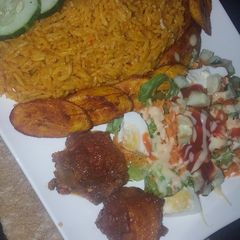 A picture of Jollof and chicken with salad and plantain.