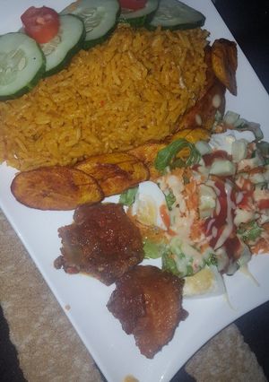 A picture of Jollof and chicken with salad and plantain.