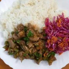 A picture of Beef stew served with rice and red cabbage.