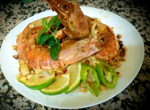 A picture of Pad thai with king prawns and lemon slices and tagliatelle rice.