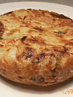 Una foto de Tortilla de patatas con cebollas, ajos y perejil
