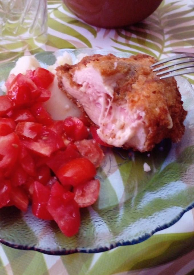 Una foto de Milanesa rellena de jamón y queso con ensalada de tomate y morón