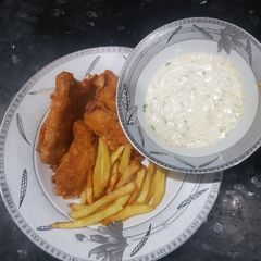 A picture of Fish and chips with tarter sauce.