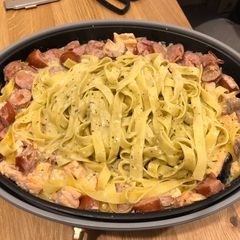 A picture of Fettucine with pesto, salmon and sausage.