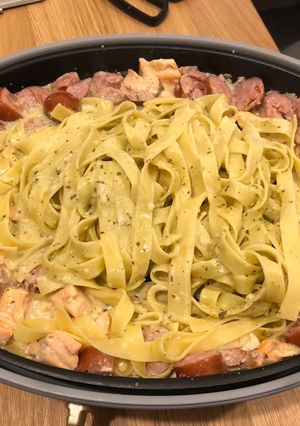 A picture of Fettucine with pesto, salmon and sausage.