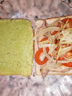 Una foto de Sándwich integral con guacamole, melva, cebolla y tomate cherry