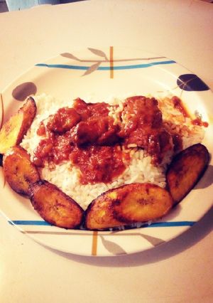 A picture of Fried plantain with white rice and stew.