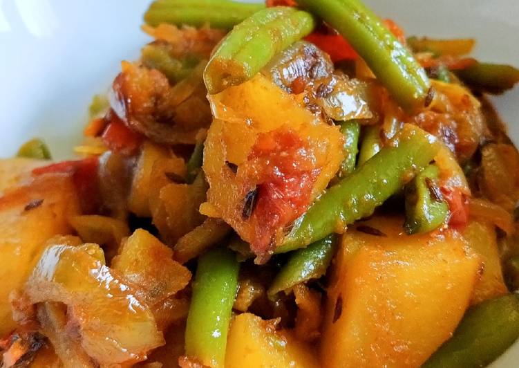 Stir Fry beans, potatoes and tomatoes in caramelized onions