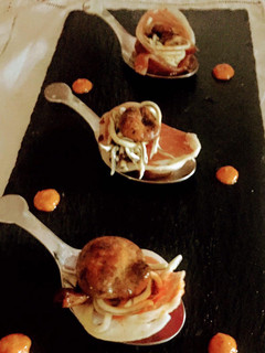 Una foto de Cucharitas de rosetones de ibérico rellenos de gulas y setas sobre base de romescu