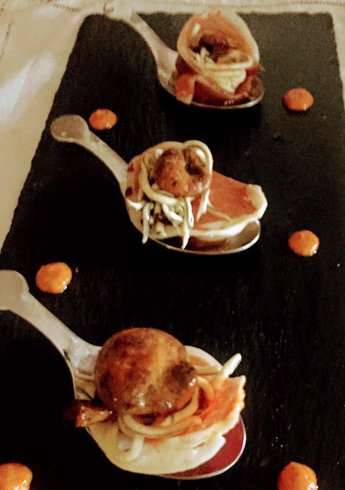 Una foto de Cucharitas de rosetones de ibérico rellenos de gulas y setas sobre base de romescu