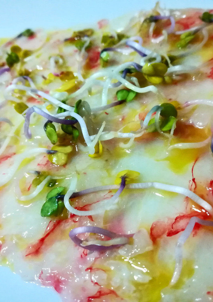 Una foto de Carpaccio de gambas rojas con brotes de raíz de rábano