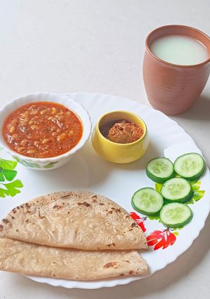 A picture of Kathiyavadi lunch :Fresh lobiya Curry, Roti, Cucumber Slices, Pickle & buttermilk.