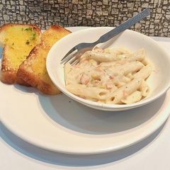 A picture of Creamy white sauce pasta with garlic toast.