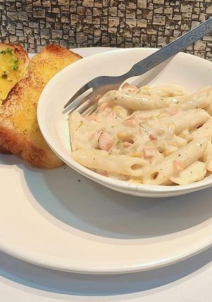 A picture of Creamy white sauce pasta with garlic toast.