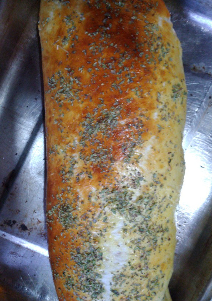 Una foto de Pan casero relleno de jamón y mozzarella, cubierto de orégano
