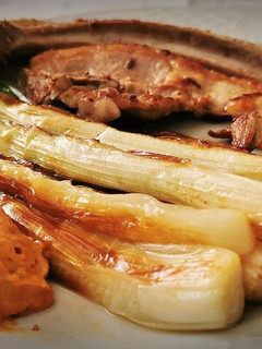 Una foto de Calçots a la plancha con guarnición de carne